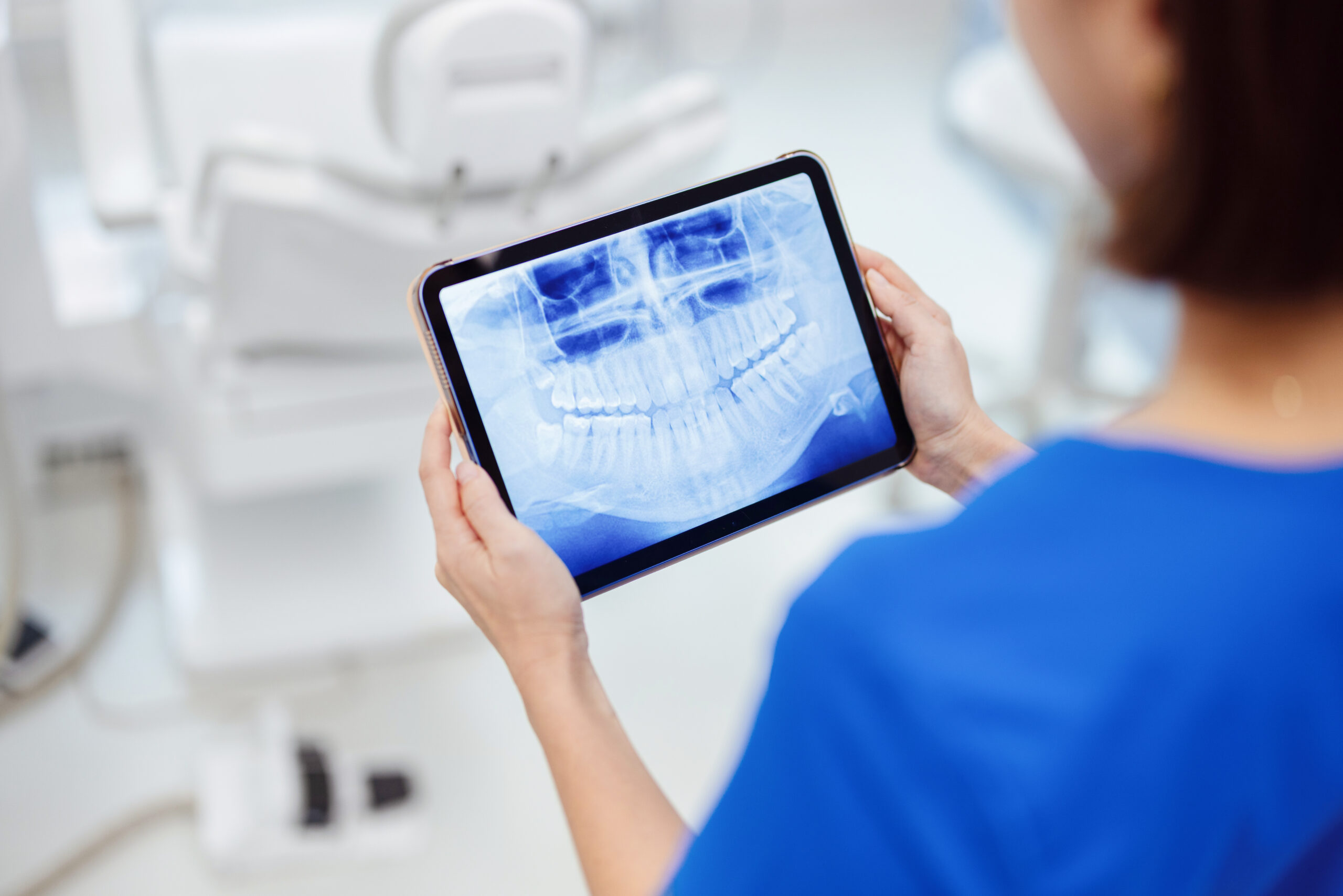 진료안내 dentist reviewing panoramic dental x ray on tablet